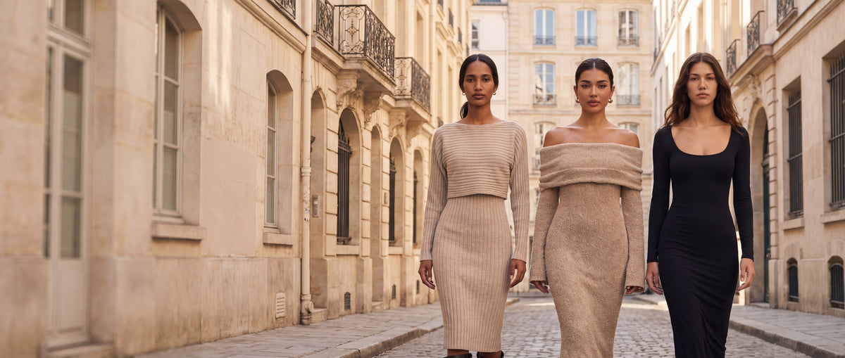 Three women walking down a sunlit European street wearing the beige ribbed knit set, the off-shoulder knit maxi dress and the black scoop-neck maxi dress