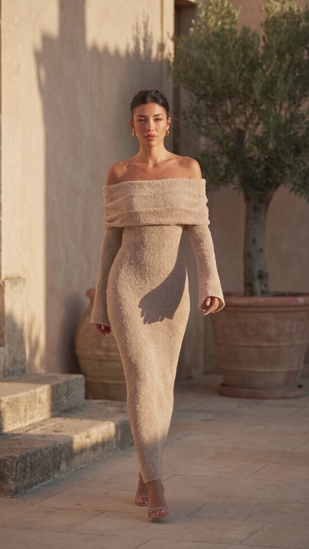 Video of the Off-Shoulder Knitted Maxi Dress worn while walking through a sunlit courtyard